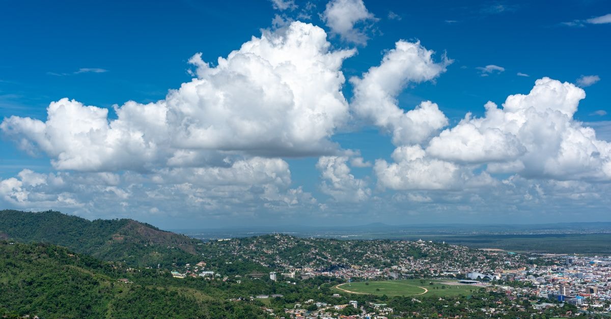 Breathtaking aerial view of Port of Spain with lush hills and clear skies, showcasing Trinidad's vibrant cityscape.