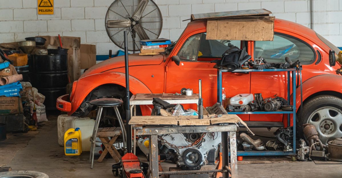 LCI Industries: Components Supplier on the Eve of a Transformative Merger Classic red car being repaired in a cluttered garage setting, filled with tools and auto parts.