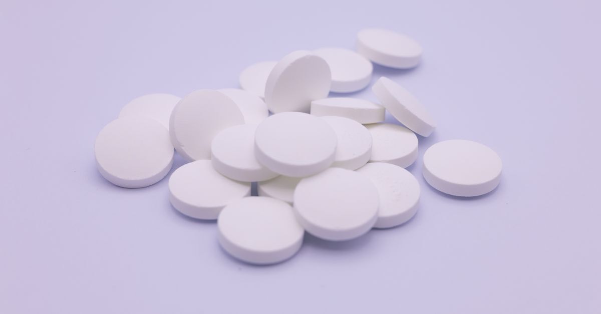 Niagen Bioscience: Brand Engine Intact, Margin Engine Slipping Assorted white tablets stacked on a soft purple surface, symbolizing medication and healthcare.