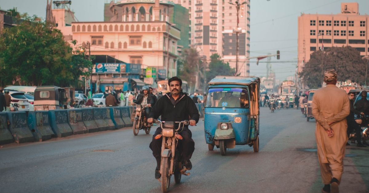 Karachi Travel Guide: A Slow Look at the City Crowded urban street scene with motorbikes and rickshaws. Vibrant city life captured outdoors.