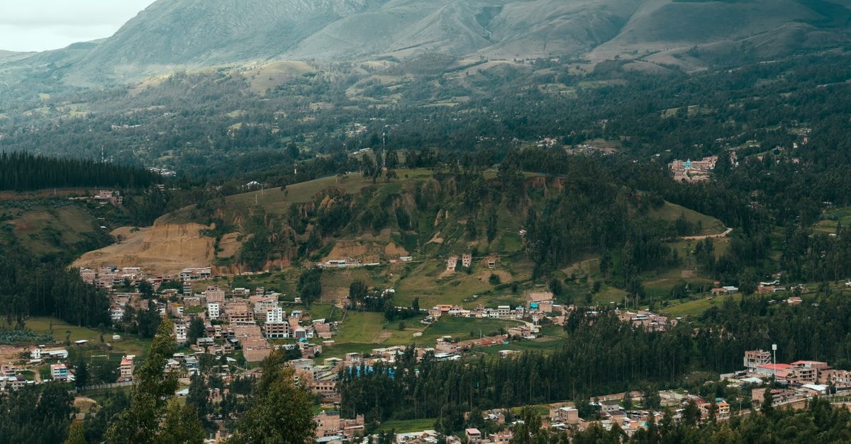 Hotel Zeus in Riobamba: Panoramic Chimborazo Vistas A beautiful aerial view of a mountainous village landscape with lush greenery and distant peaks.