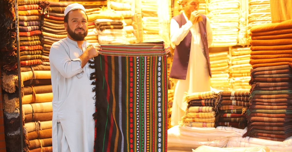 Vibrant market scene with traditional rugs and textiles on display at a cultural bazaar.
