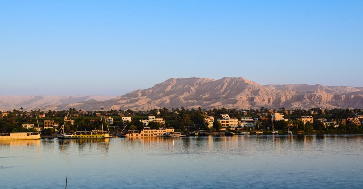Esna Travel Guide: A Quiet Nile Town Worth Slowing Down For Captivating view of the Nile River with lush greenery and distant desert mountains in Egypt.