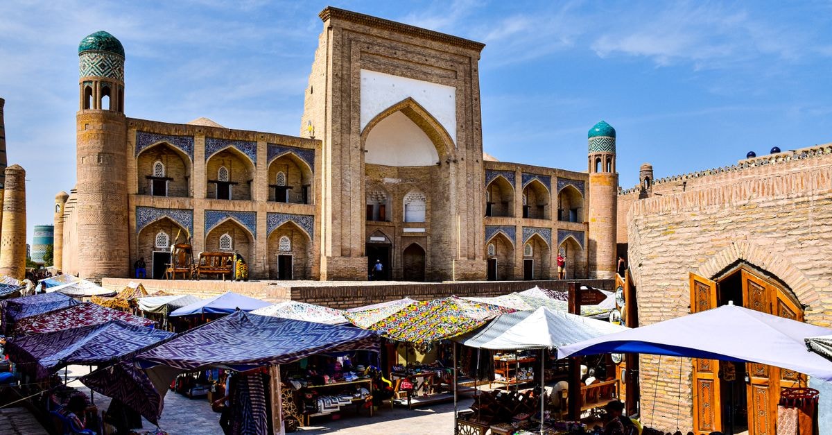 A bustling market scene in Khiva, showcasing stunning Central Asian architecture under a clear blue sky.