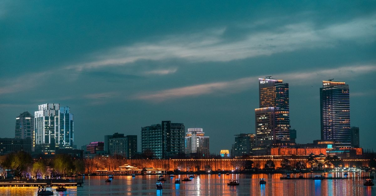 Ningbo Travel Guide: A Slower, Savoury Encounter with Zhejiang's Port City Beautiful urban skyline at dusk, reflecting on calm water with vibrant city lights.