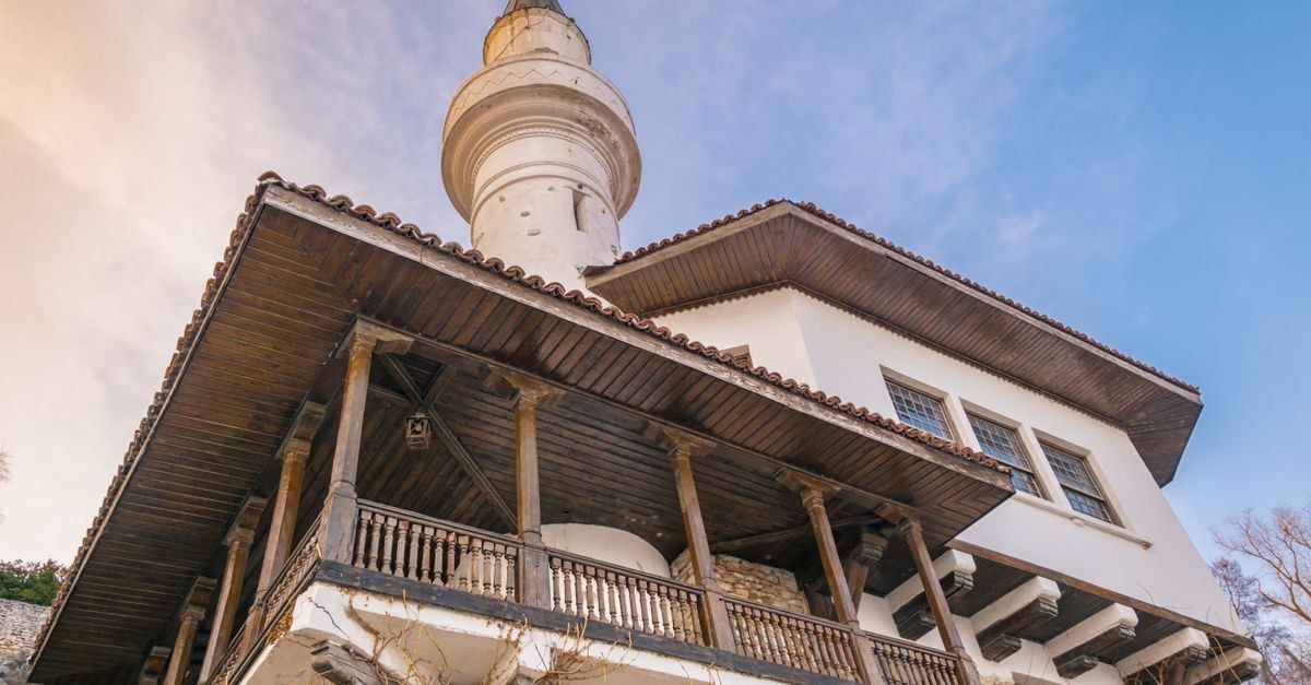 Discovering Razgrad: A Quiet Bulgaria Travel Guide for Slow Travelers Low angle view of an architectural facade featuring a wooden balcony and tower against a blue sky.
