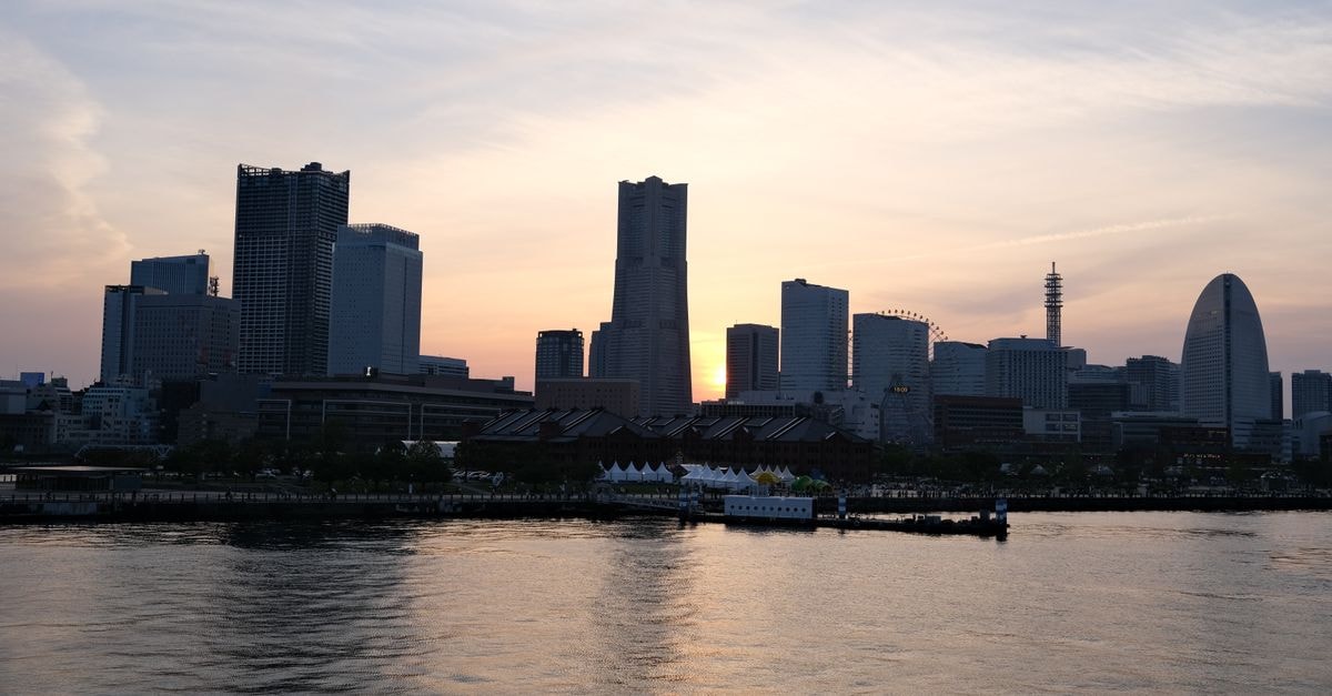 JR-East Hotel Mets Premier Yokohama Sakuragichō: One-Minute Step from Sakuragichō Station Stunning sunset view of Yokohama's skyline with reflections on the water, capturing modern architecture and urban beauty.