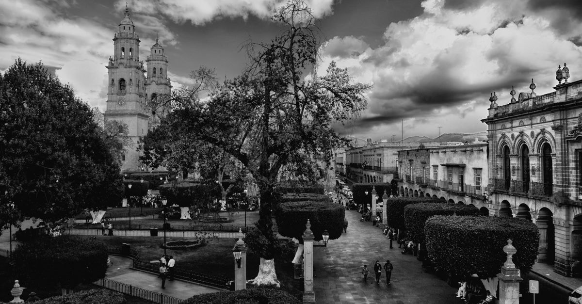 Dramatic black and white photo of a historical cityscape showcasing a cathedral and bustling street.