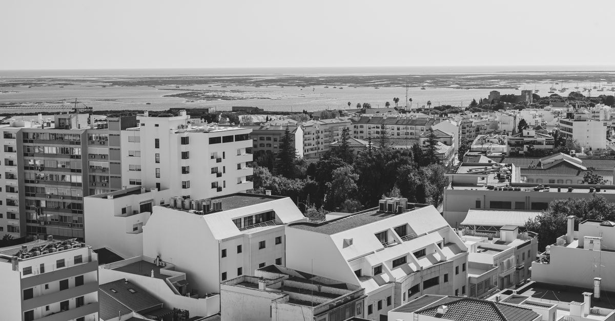 EVA Senses Hotel in Faro: Marina-Front Stay with Ria Formosa Views Black and white aerial view of Faro's urban landscape with the Atlantic in sight, capturing Portugal's coastal charm.