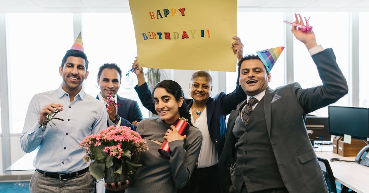 JioBlackRock launches first GIFT City World Equity fund Happy colleagues celebrating a birthday in an office with hats and balloons.