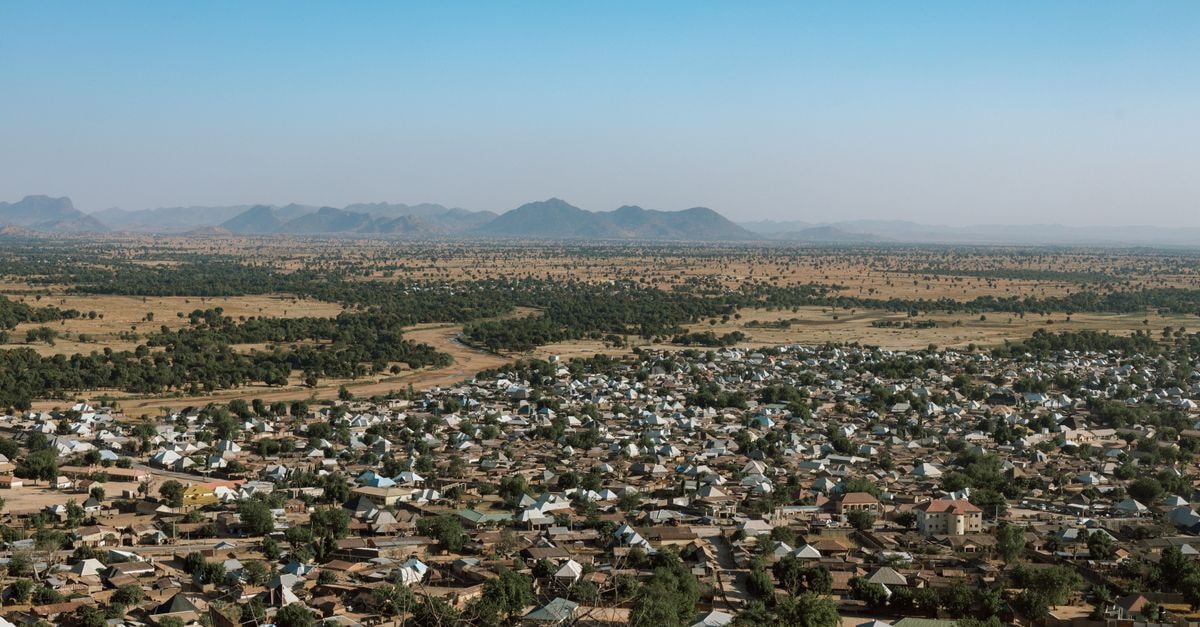 Hamdallah Hotel in Tamale: A Central High Street Stay Aerial view capturing a vast rural settlement with distant mountains and open fields under a clear blue sky.