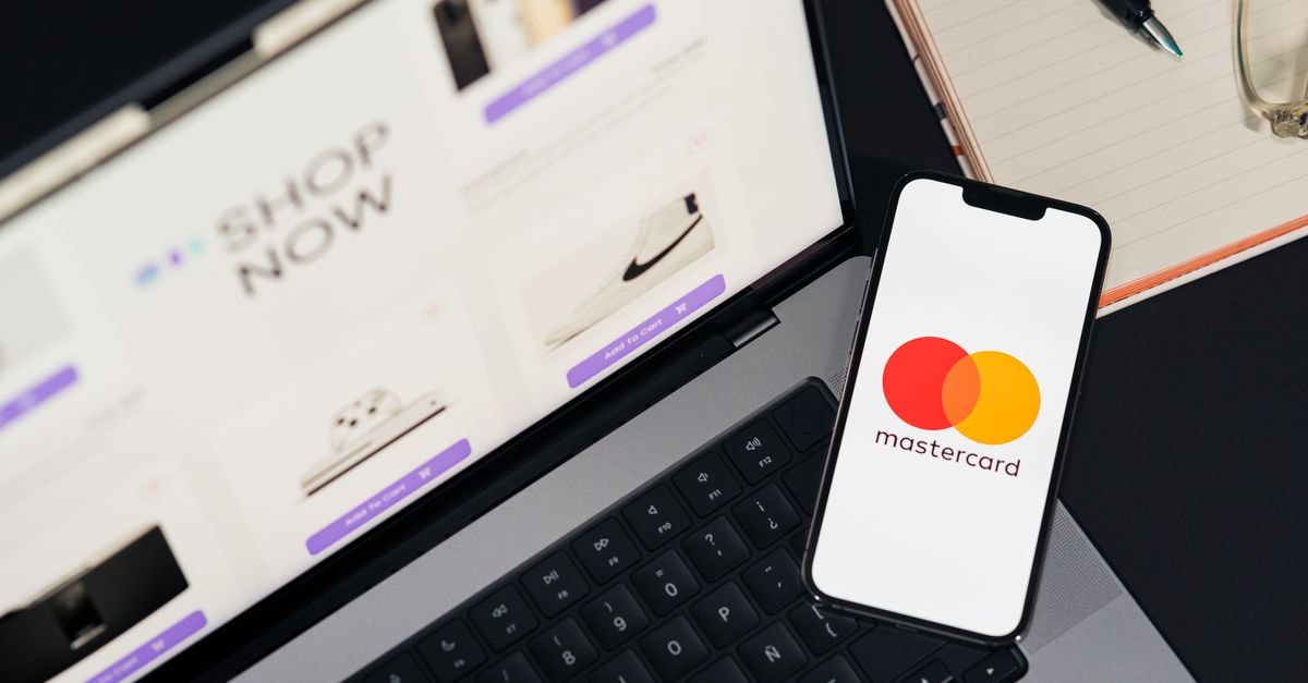 Laptop and smartphone with Mastercard logo, illustrating online shopping and digital payments.