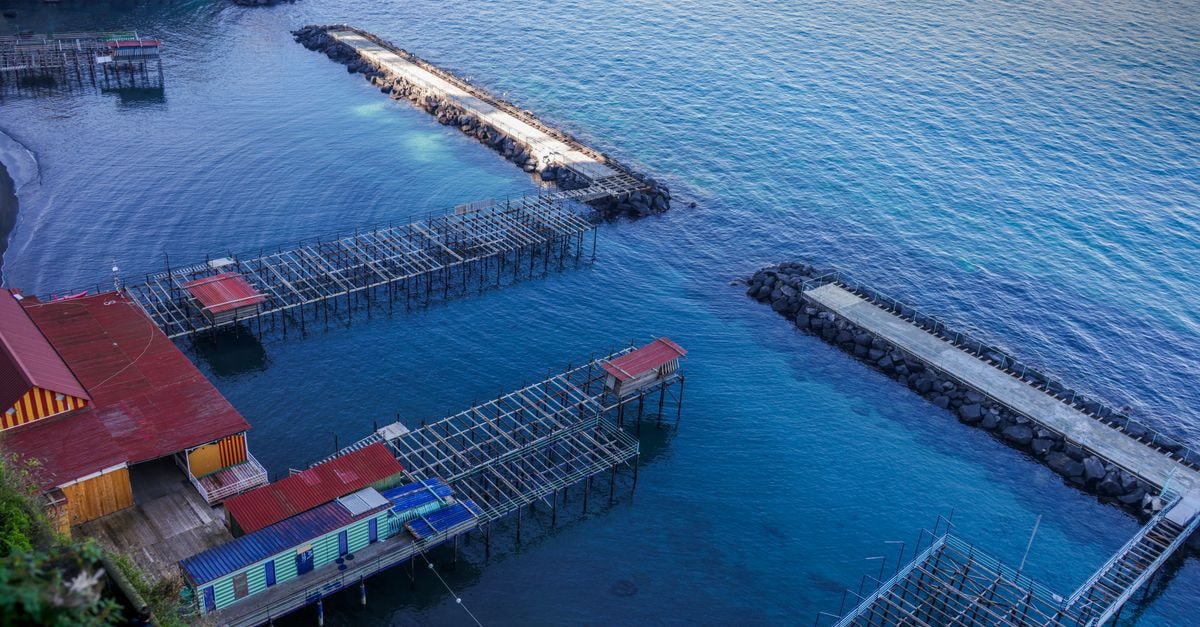 A scenic aerial view of coastal fishing piers with vibrant colors and serene waters, captured at dawn.