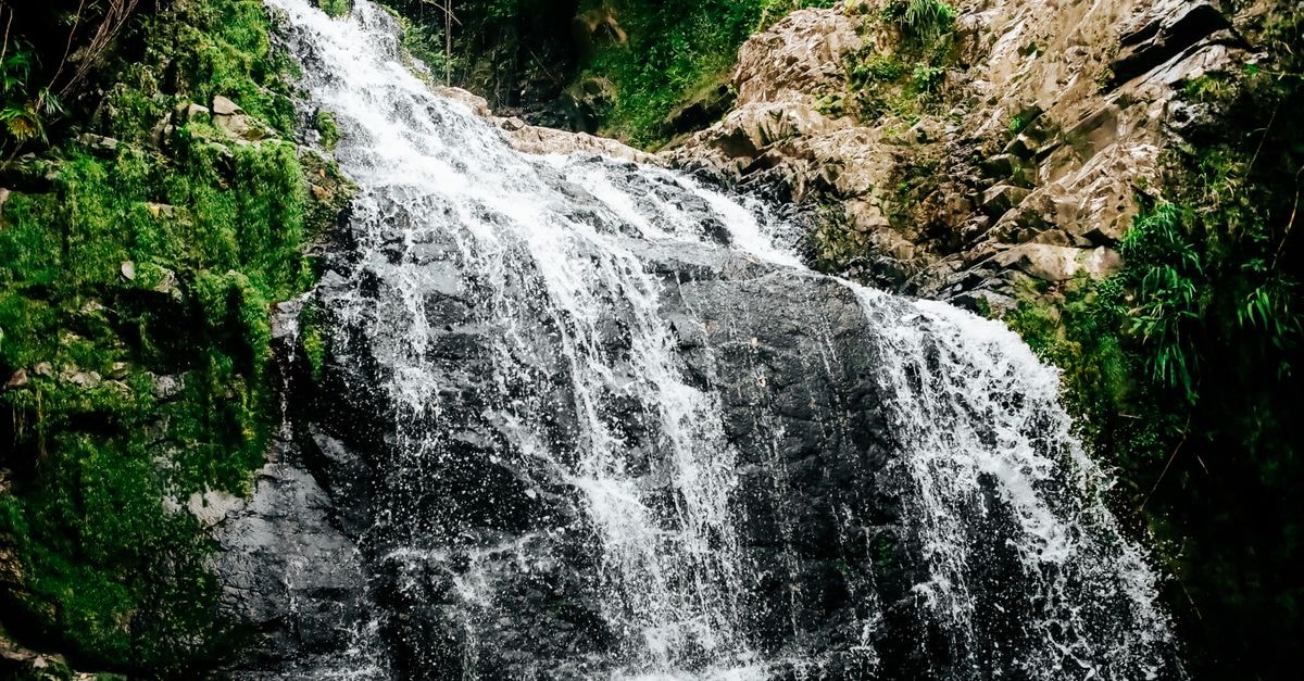 Jacmel Travel Guide: Waterfalls, Beaches and Slow Southern Days A mesmerizing waterfall cascading over lush green rocks in a natural outdoor setting.