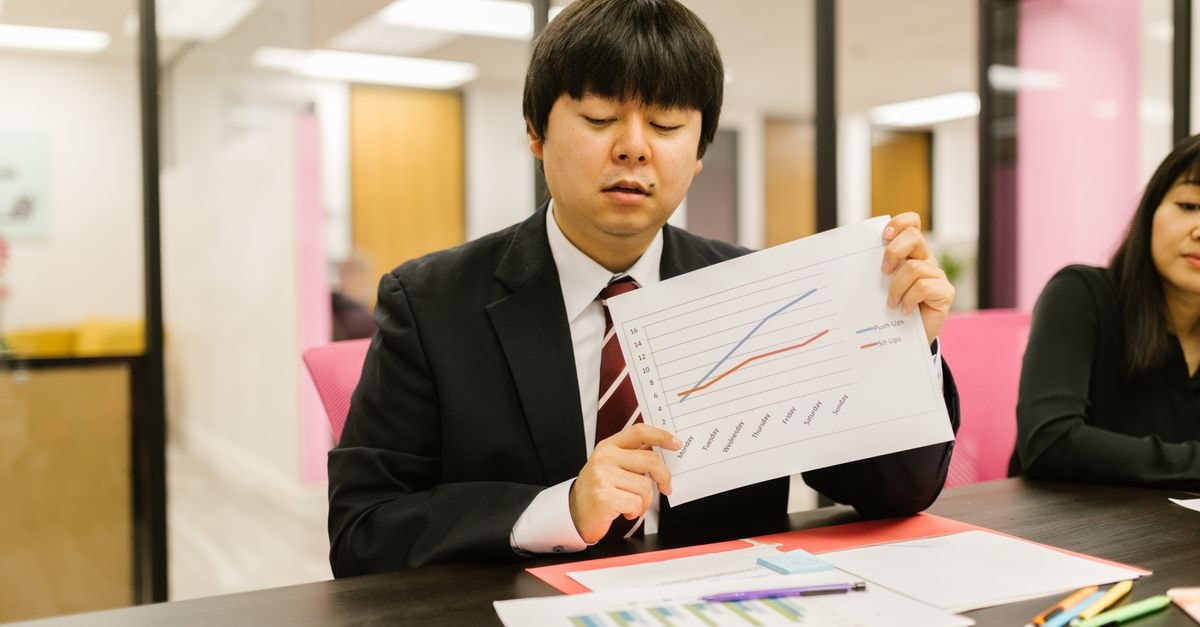Jensen Huang becomes world's 7th-richest as Nvidia hits intraday record high Two professionals in business attire discussing graphs during an office meeting.