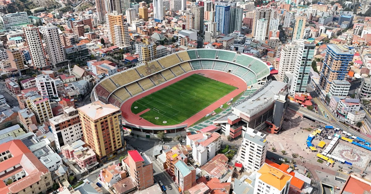 Aerial shot of a stadium in La Paz, Bolivia, surrounded by urban skyscrapers and cityscape.