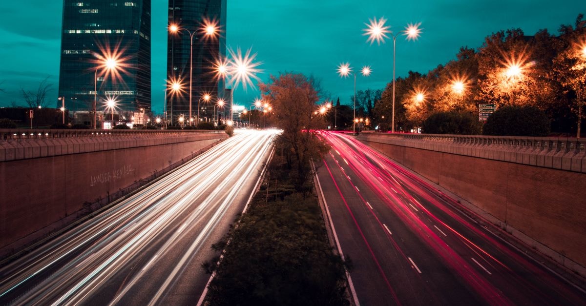 Dynamic night shot of vibrant traffic light trails under Madrid's lit skyscrapers.