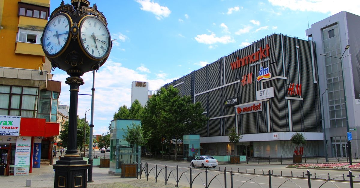 Hotel Satu Mare City in Satu Mare: A Central Garden Retreat Charming street scene in Râmnicu Vâlcea, featuring an ornate clock and modern shopping center.