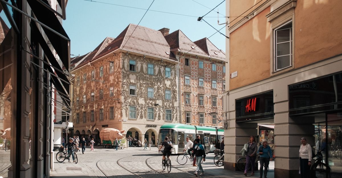 NH City Graz: Park-Edge Stay in a UNESCO Old Town Vibrant street view in Graz, Austria, featuring historic architecture, trams, and active pedestrians.