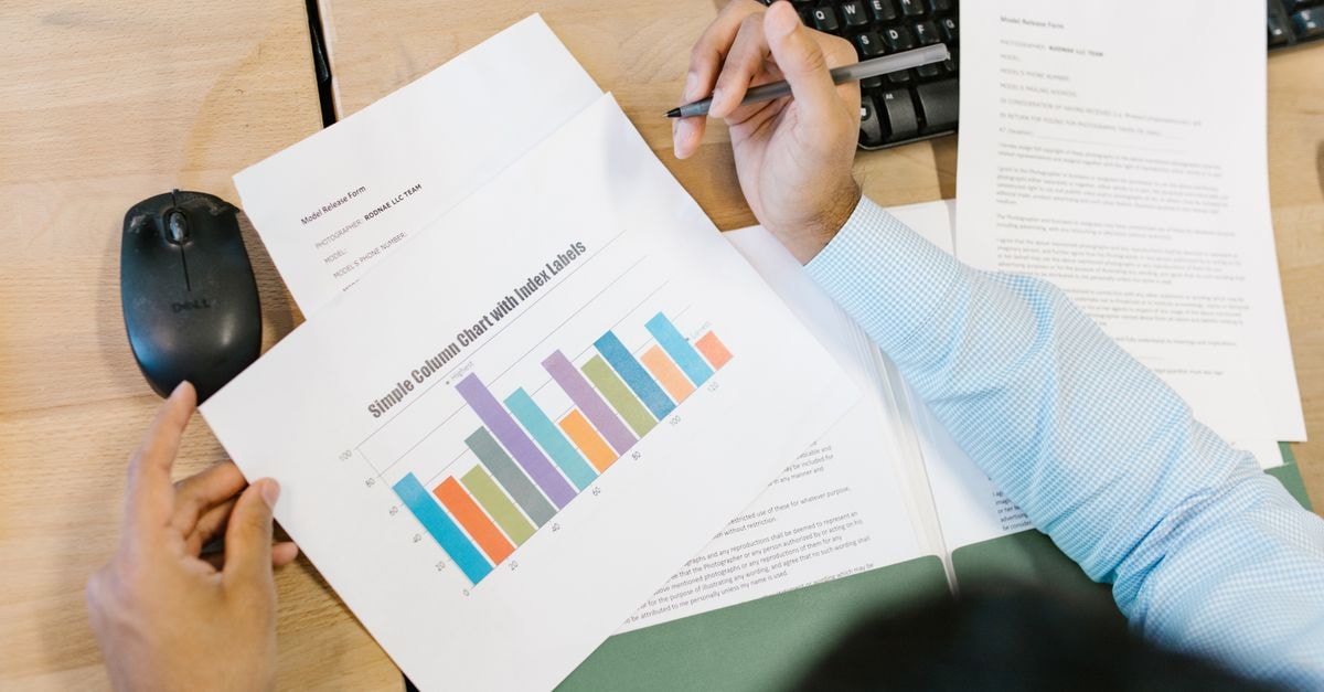 A business analyst reviews a colorful bar chart and documents at a desk, indicating data analysis.