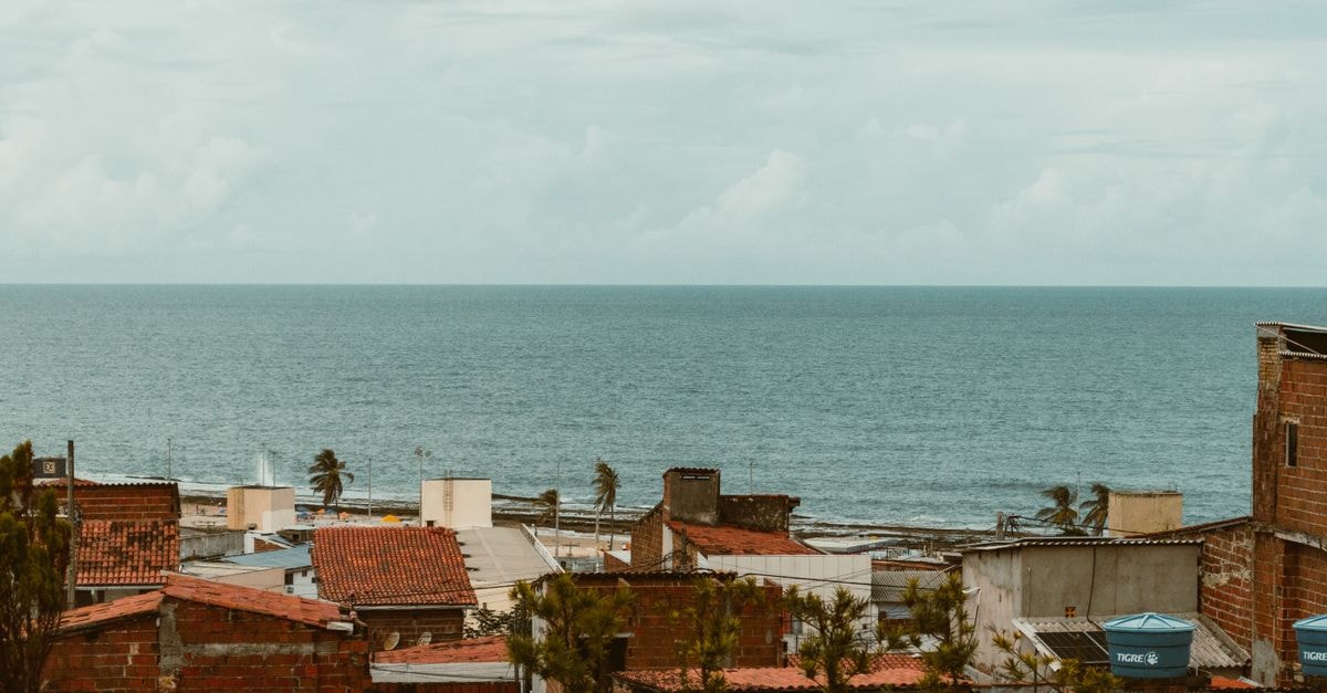 Hotel Verdes Vales in Juazeiro do Norte: A Family Stay With Pool, Restaurant and Event Spaces A picturesque view of rooftops and the ocean in Natal, Brazil, with an overcast sky.