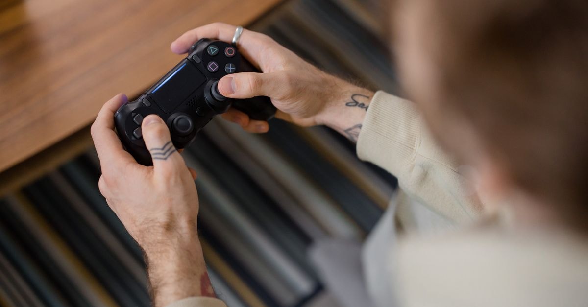 No Rest for the Wicked full release pushed from October 2026 to March 2027 Detailed view of a person holding a gaming controller indoors, emphasizing the gameplay action.