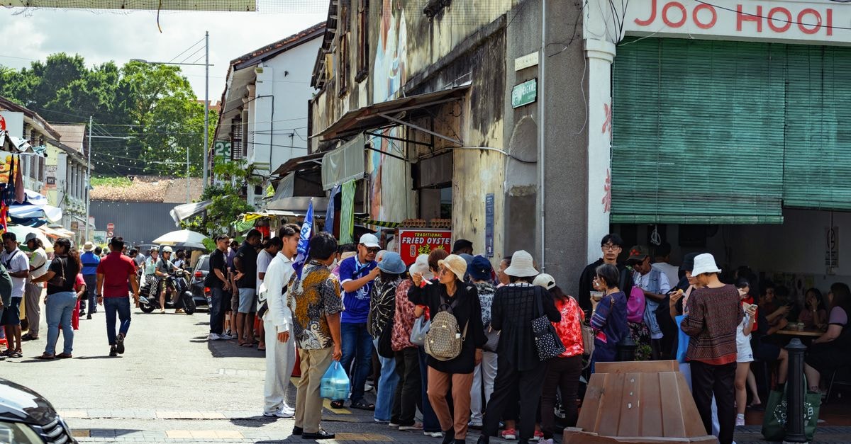 Vibrant street life in Georgetown, Penang with crowded eateries and diverse crowd.