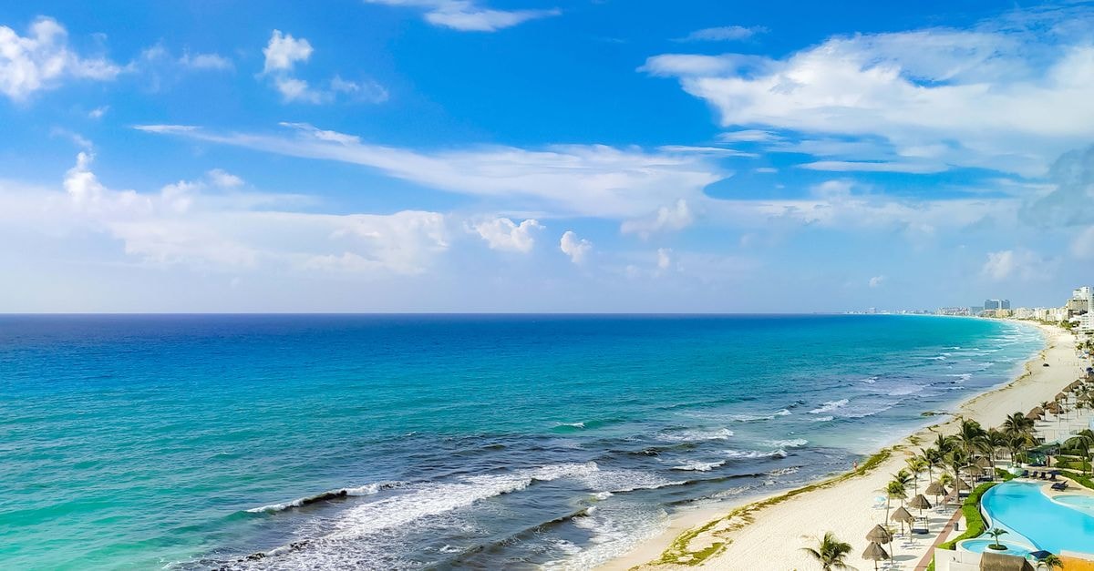 Aerial view of Cancún's coastline with turquoise sea, sandy beaches, and clear skies.