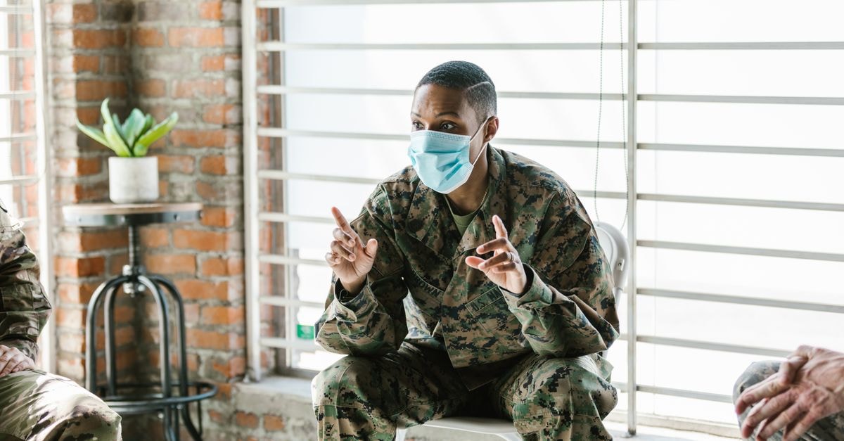General Dynamics Q2 beat and record backlog shape its investment case A military soldier wearing a facemask converses indoors, symbolizing communication and safety.