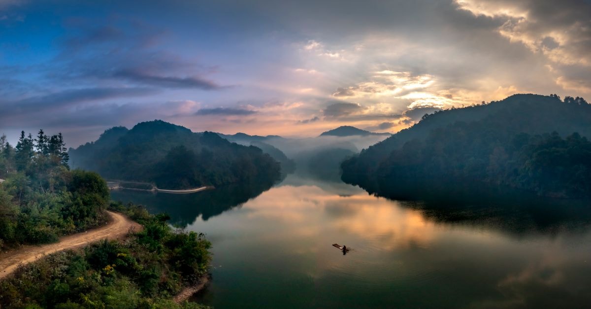 Chenzhou Travel Guide: Misty Lakes and Red-Rock Landscapes Breathtaking view of a tranquil lake surrounded by misty mountains at sunrise.