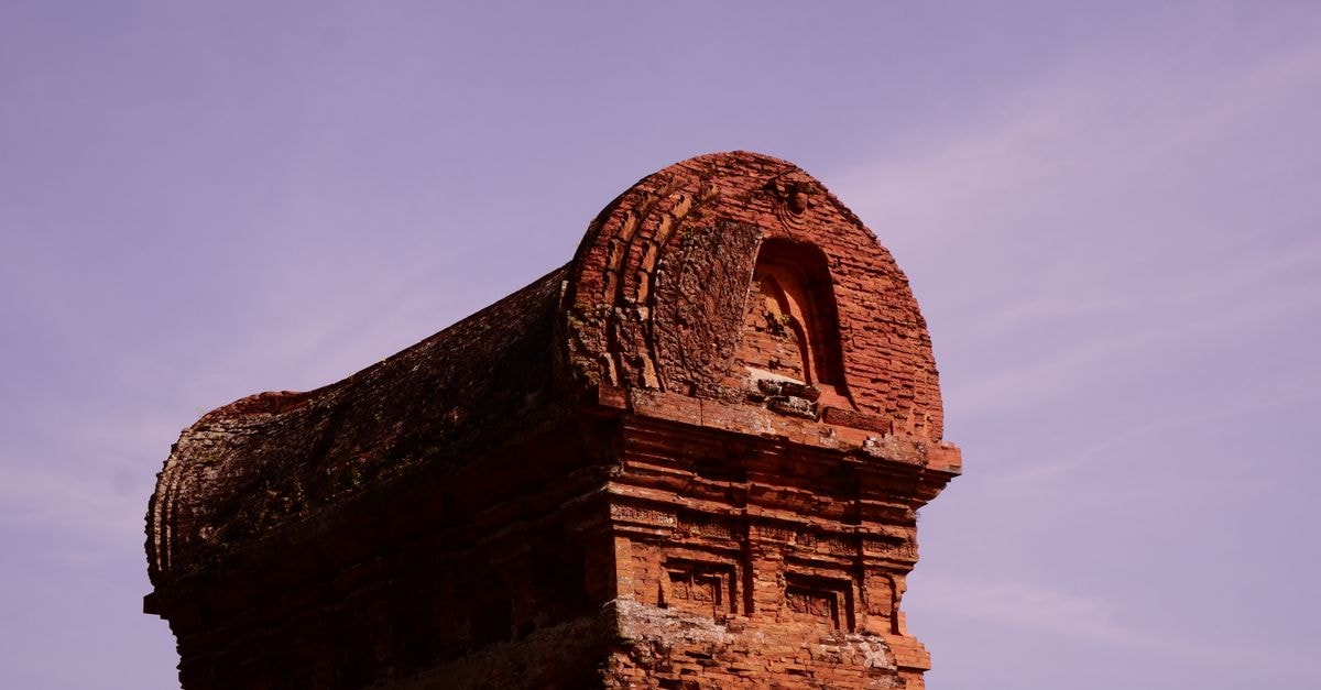 An Nhon, Gia Lai Travel Guide: Quiet Heritage in Vietnam's Central Highlands A close-up view of the historic Banh It Tower in Vietnam with a vibrant purple sky backdrop.