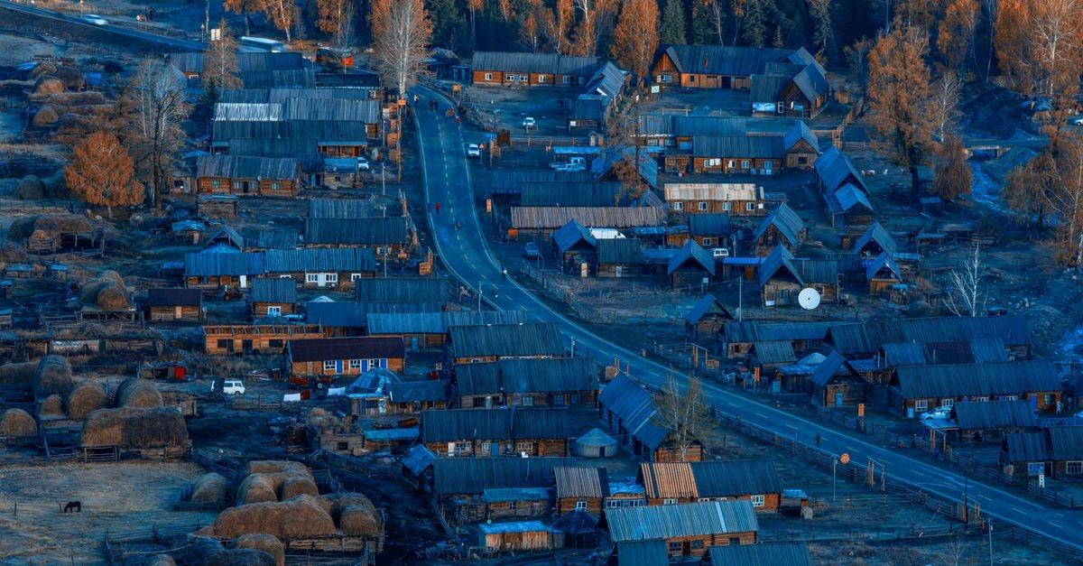 A picturesque aerial view of a rural village surrounded by autumn foliage, showcasing traditional wooden houses.