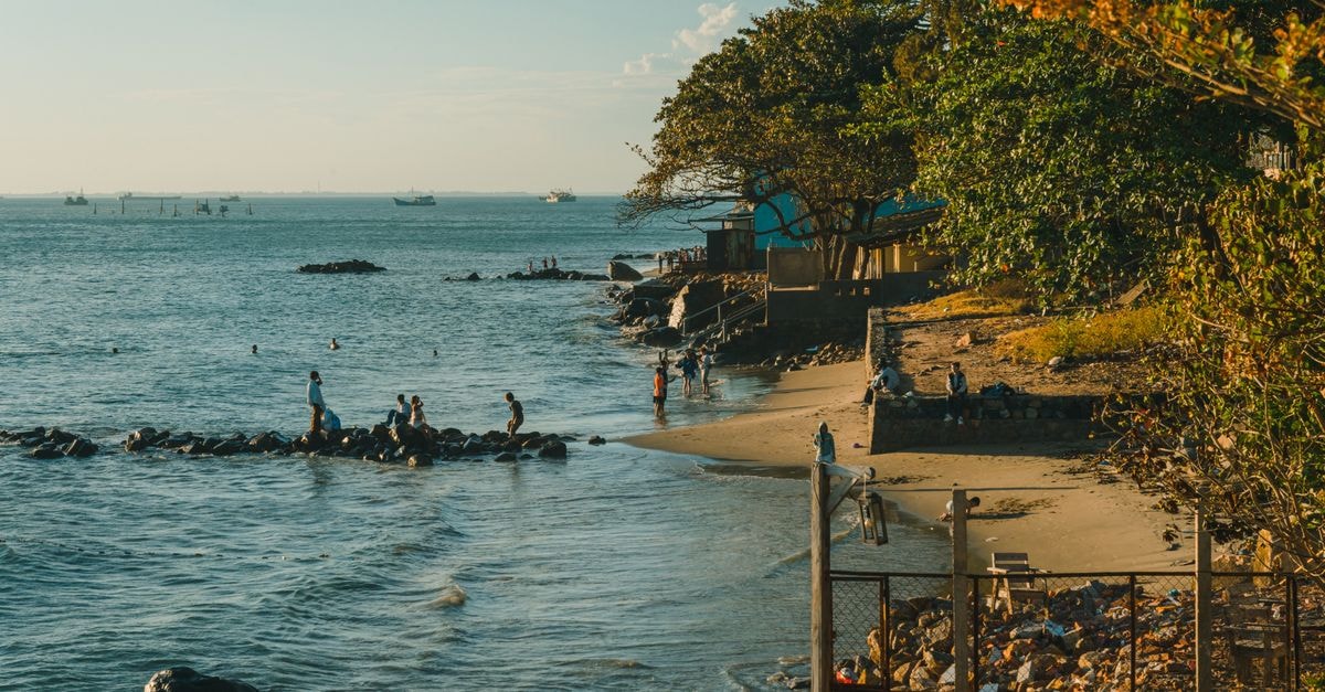 Vitória Travel Guide: Island Capital Vibes in A tranquil beach scene with people enjoying the shoreline under a clear blue sky.