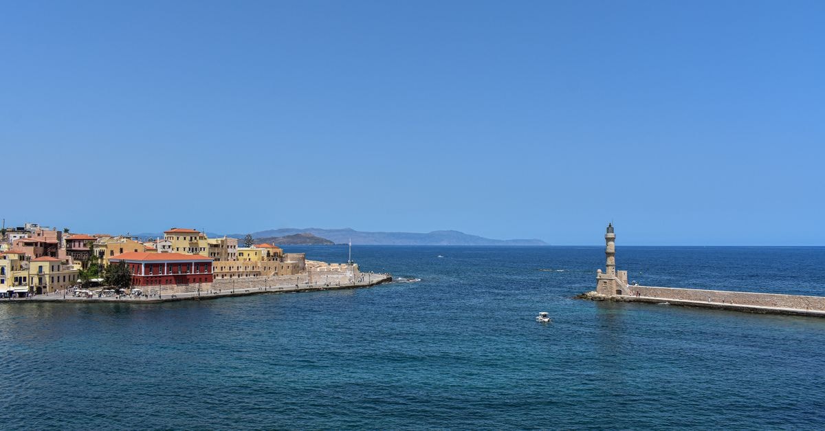 Antel Suites in Chania: A Minimalist Urban Stay by the Old Town Scenic view of Chania harbor with historic lighthouse under clear blue skies.