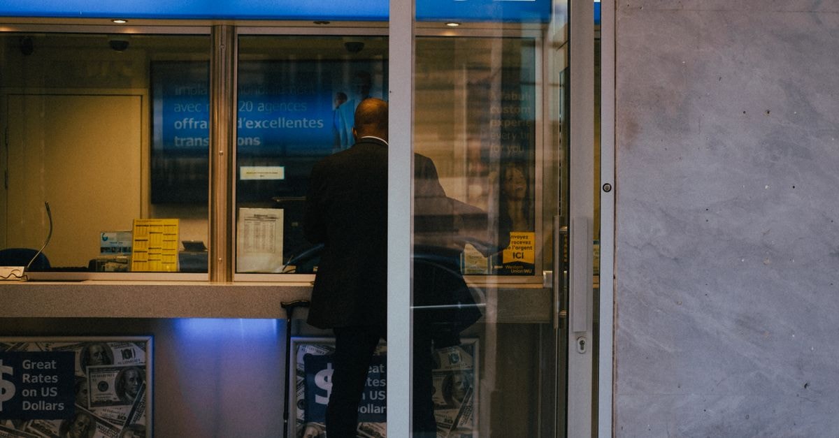 Citi and Mastercard Debut Smart Subscriptions Globally in the UAE Man at a currency exchange office window, showing currency rates inside a bustling city.