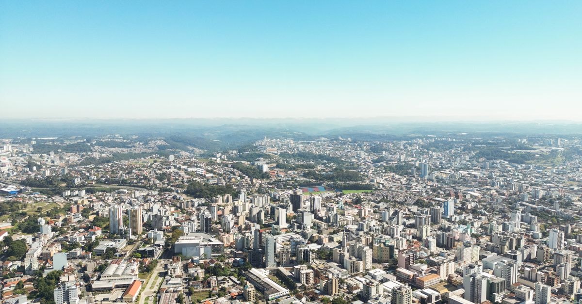 Alji Hotel in Indaiatuba: Modern Stays Near Viracopos Airport Stunning aerial view of Caxias do Sul's urban cityscape under a clear blue sky.