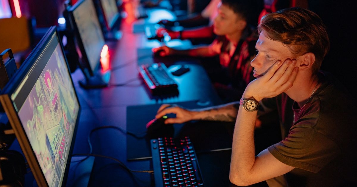 Brazil's online gambling ban reshapes payments and operator share prices Gamers intensely focused on a computer game during an online esport competition in a dimly lit arena.