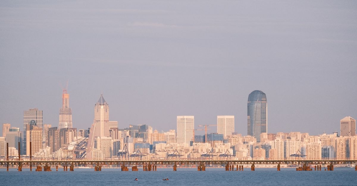 Stunning view of a city skyline with skyscrapers and a waterfront under a pink sunset light.