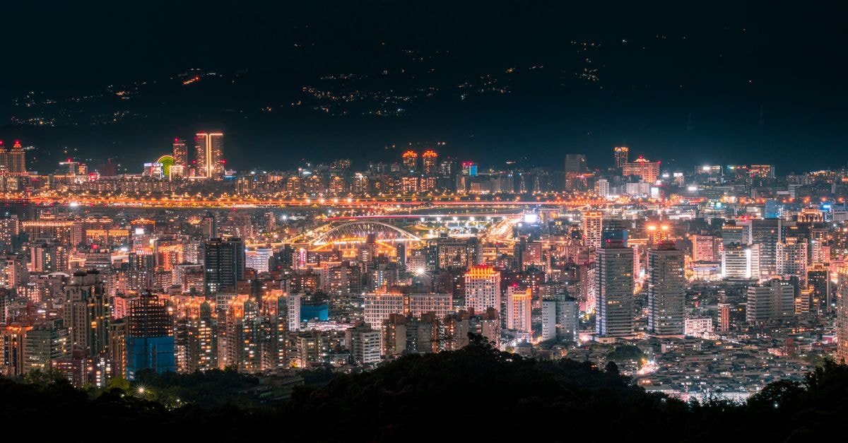 A stunning evening cityscape of Taipei with illuminated skyscrapers and vibrant city lights.