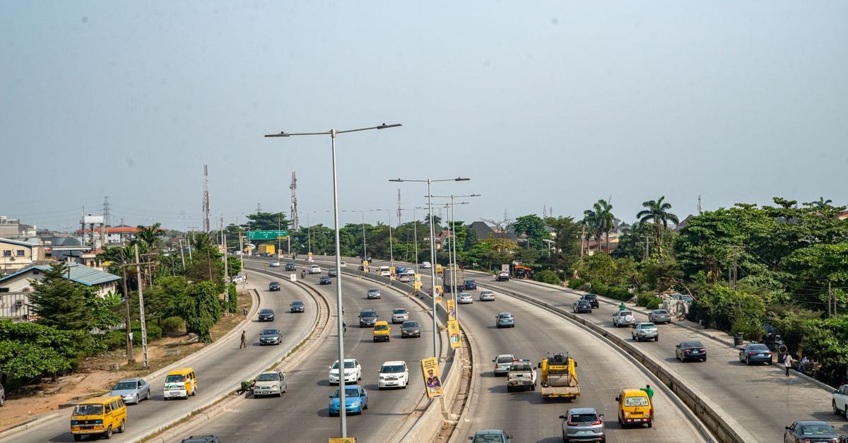 An aerial view of a bustling highway with palm trees, vehicles, and clear skies.
