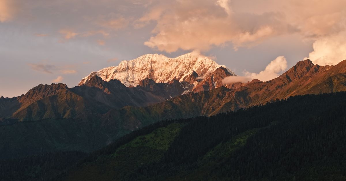Kangding Travel Guide: A Highland Town with Tibetan Flavor Stunning sunset over Namcha Barwa Peak in Tibet, casting warm hues on snow-covered mountains.