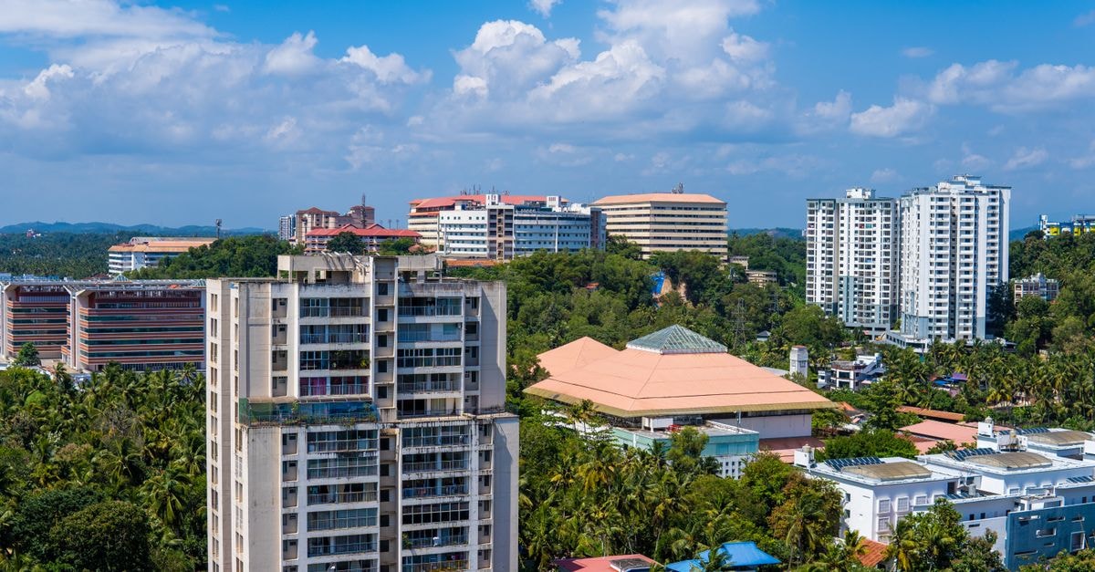 Cliff Embassy Banquet And Suites, Shivamogga: A Palatial Four-Story Stay on Kuvempu Road A bustling cityscape showcasing diverse architecture among lush greenery under a bright blue sky.