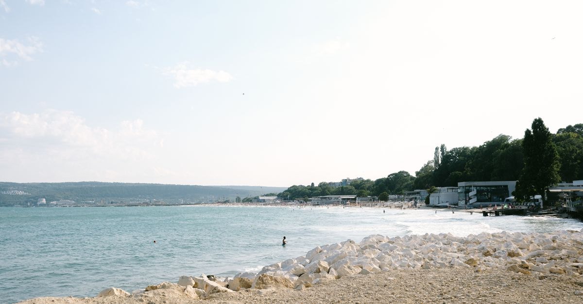Hotel Color in Varna: A Quiet Street Near the City Center A serene summer day at Varna Beach with clear skies and gentle waves.