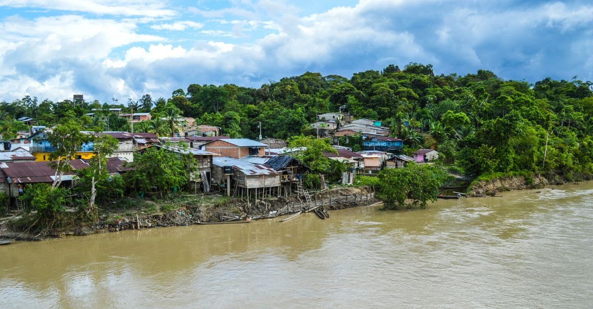 Aerial view of Puerto Nuevo, Chocó, Colombia, with lush greenery and riverside houses.