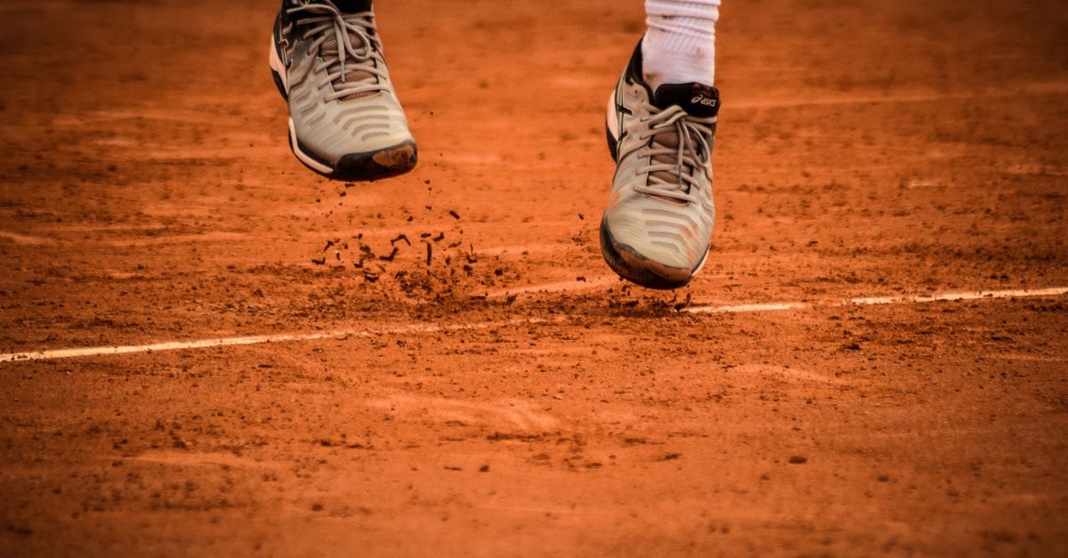 Hotel Santa Cristina, Durazno — A Relaxing Stop on Ruta 5 Close-up of an athlete's shoes mid-jump on a clay tennis court.