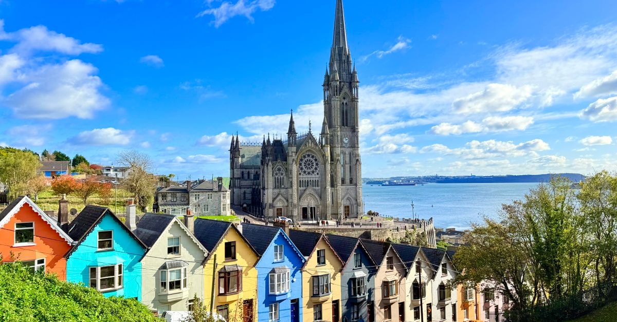 Vibrant colorful houses and cathedral in Cobh, Ireland with Atlantic Ocean backdrop.