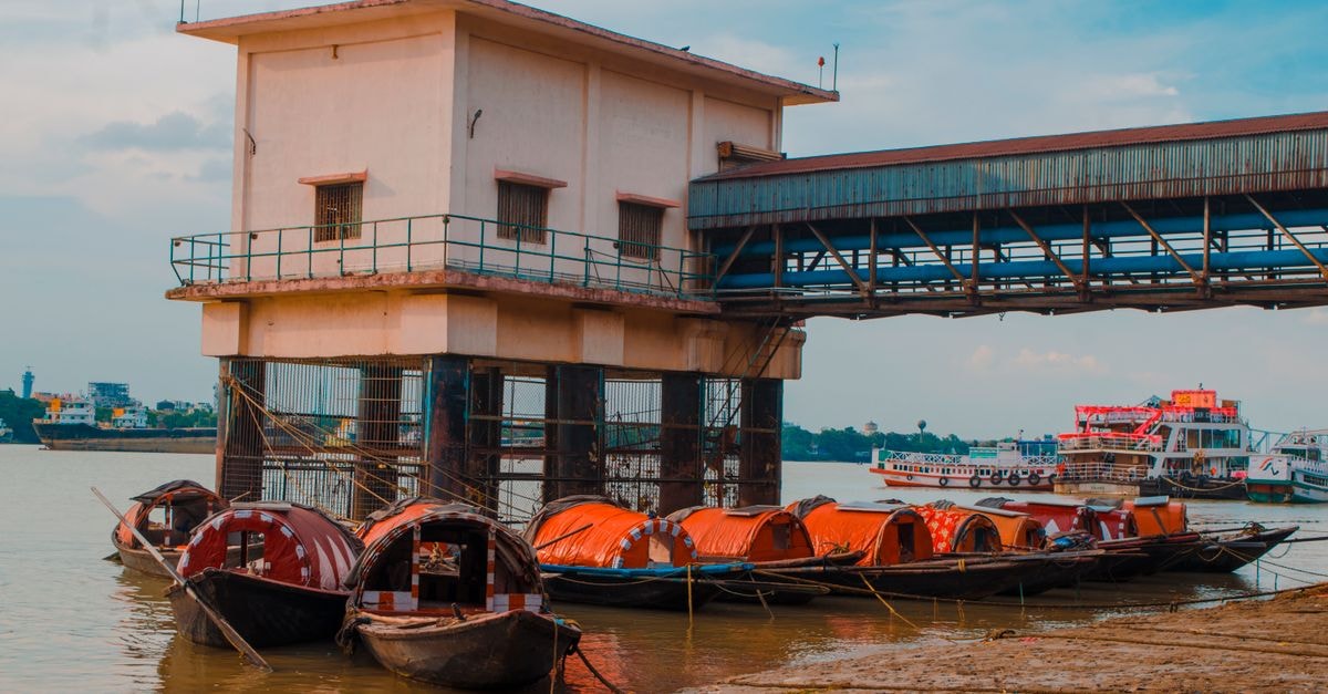 Kolkata Travel Guide: A Slow, Flavor-First Introduction Wooden boats moored on the Ganges Riverbank next to a pier building in India.