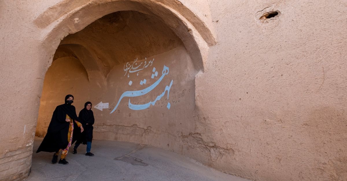 Kashan Travel Guide: A Quiet Doorway into Old Iran Two women stroll through a traditional archway in Yezd, Iran, showcasing its historic architecture.
