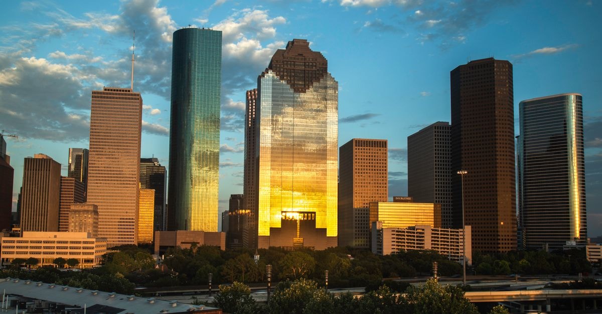 View of Houston's downtown skyline with a beautiful sunset reflection on skyscrapers.