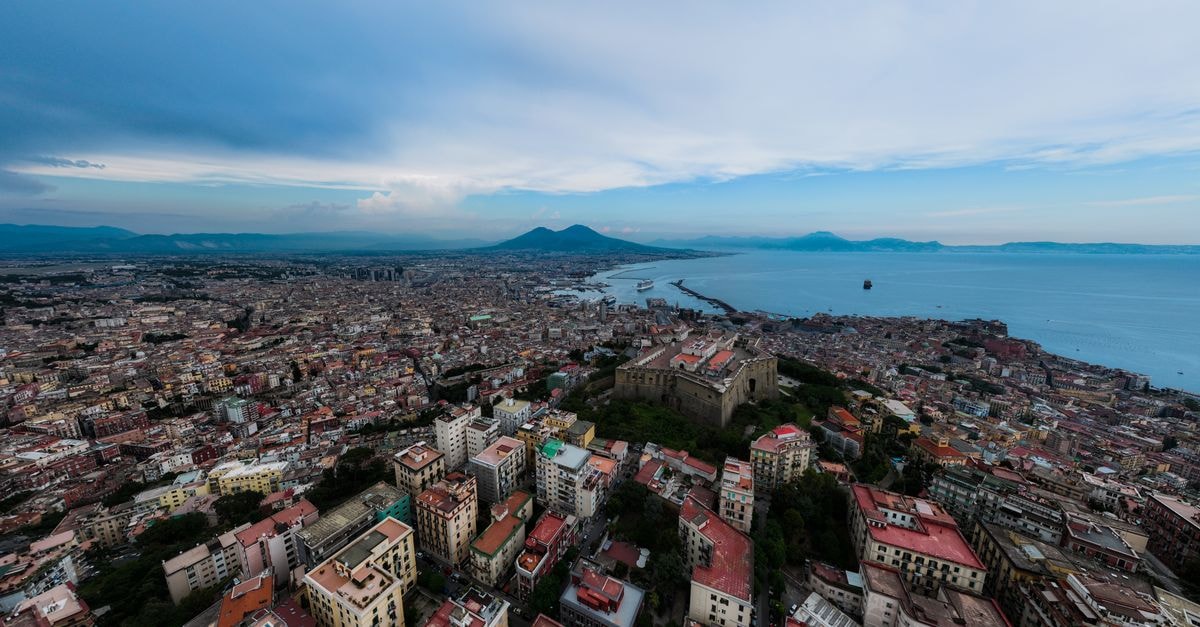 B&B Chiaia 32 in Naples: A Restored Residence on the Historic Via Chiaia Panoramic aerial view of Naples, Italy, featuring Mount Vesuvius and the Mediterranean Sea.